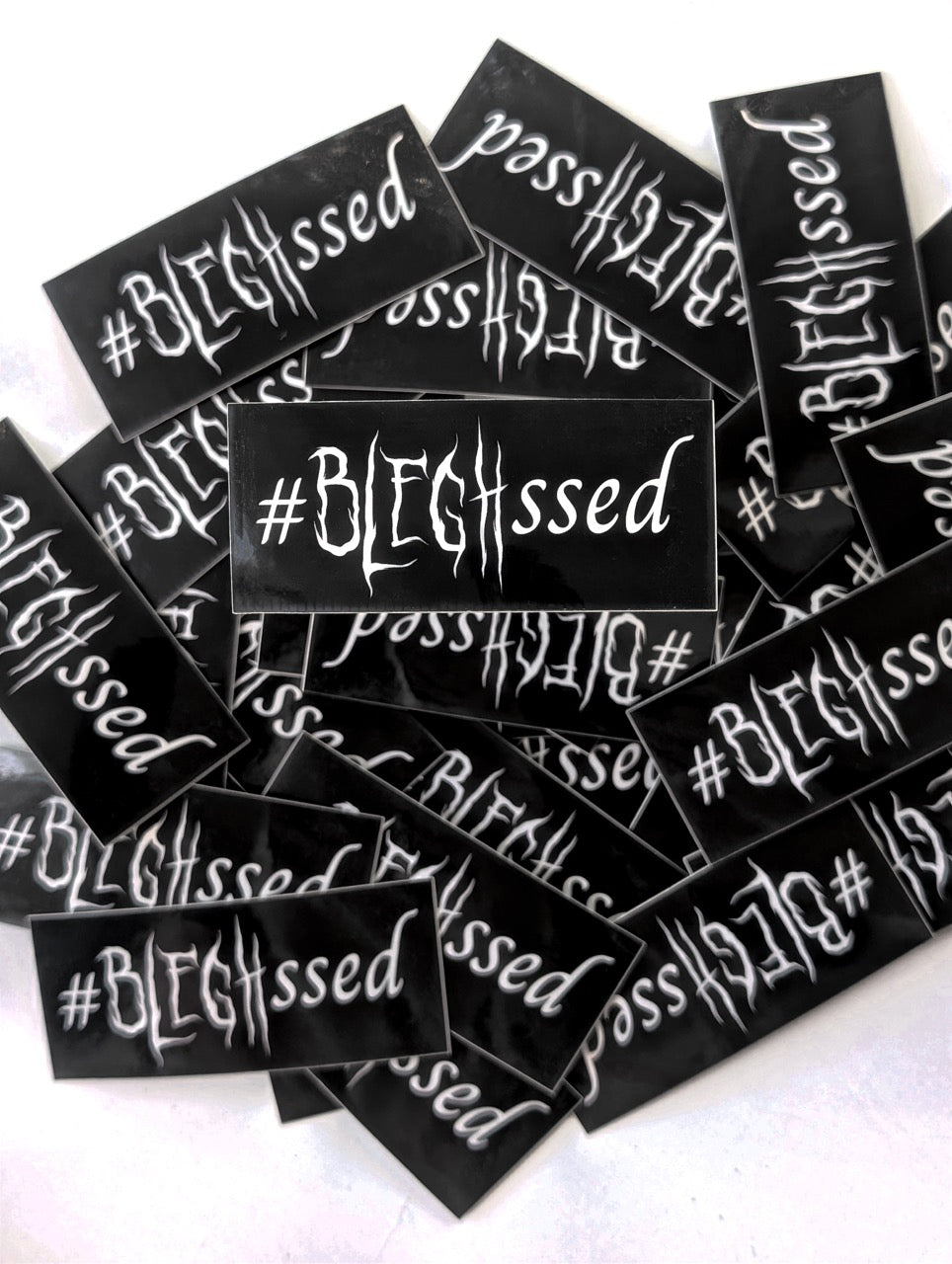 Multiple black stickers with '#BLEGHssed' text on a white background