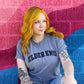 Person with colorful hair and tattoos wearing a 'Elder Emo' shirt against a multicolored textured wall.