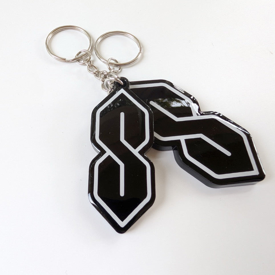 Black and white keychains with a logo on a white background