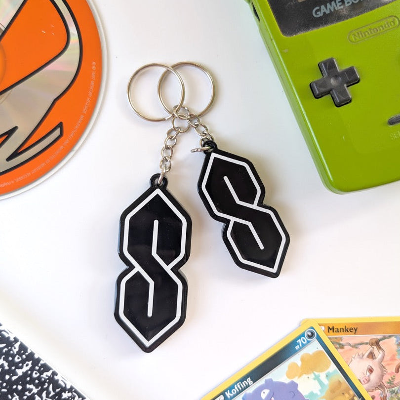 Green Game Boy Color with black and white keychain, orange disc, and trading card on a white surface