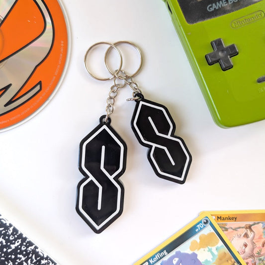 Green Game Boy Color with black and white keychain, orange disc, and trading card on a white surface